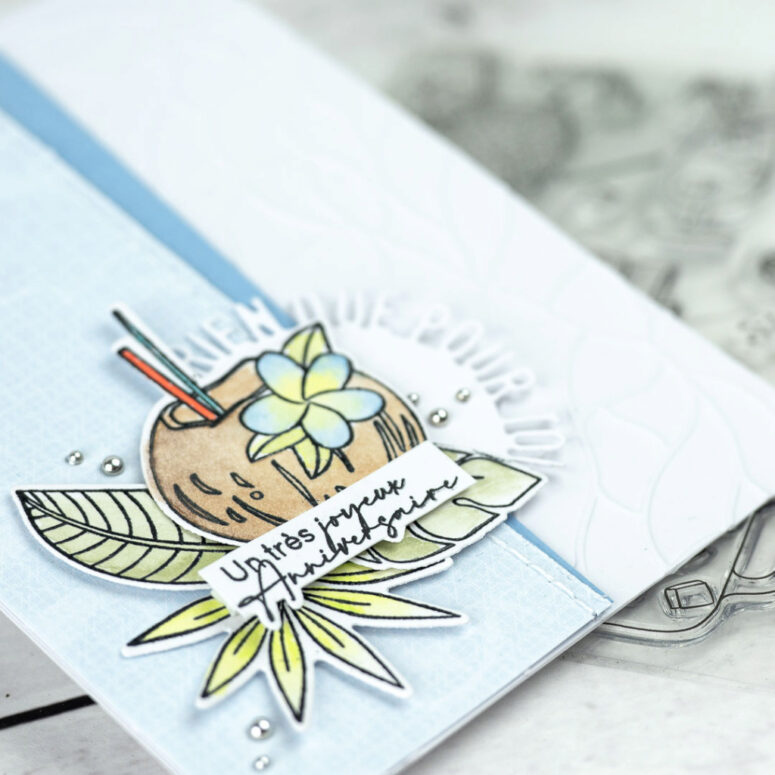Carte d'anniversaire bleu avec un joli cocktail noix de coco, et des feuillages exotiques.